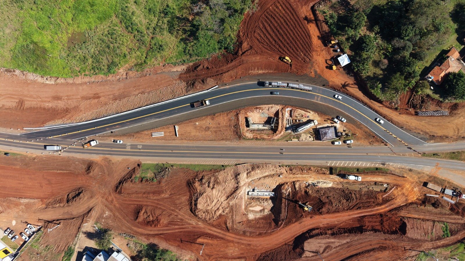 Obra de fundação e terraplenagem em execução em trecho da concessão EPR Litoral Pioneiro, com maquinário e pista já pavimentada ao fundo