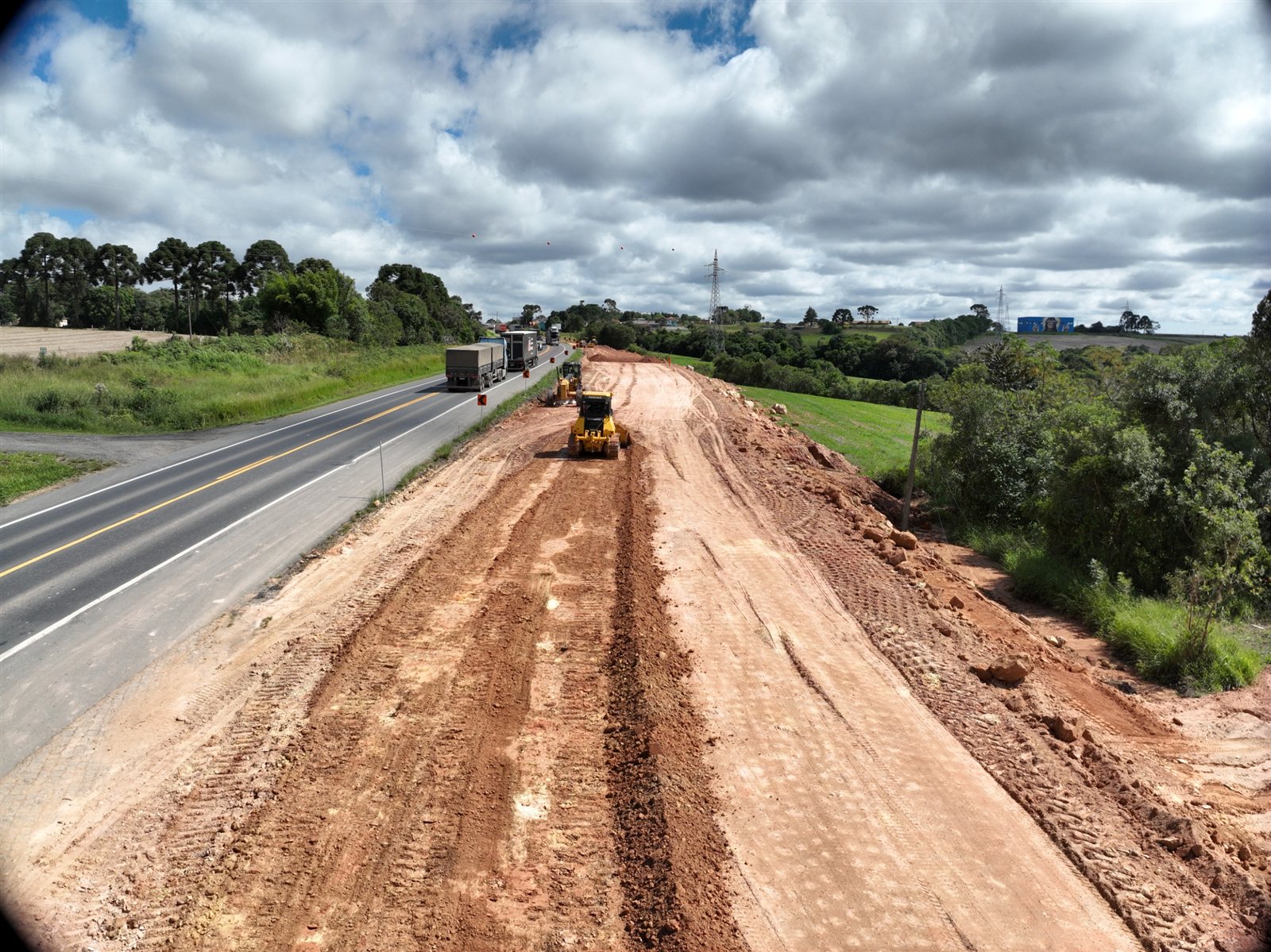 Terraplenagem para a nova faixa da BR-277 no trecho entre Palmeira e Irati, no Paraná, com trator de esteira e caminhões na obra